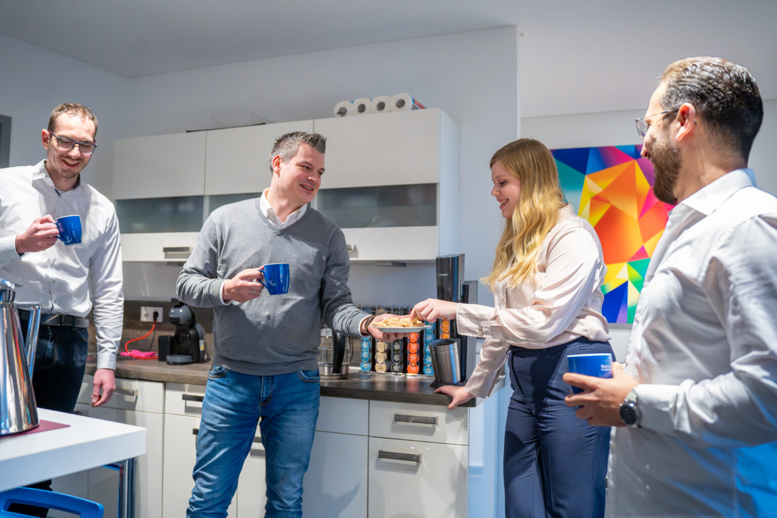 Vier Personen lachen und trinken Kaffee in der Kueche