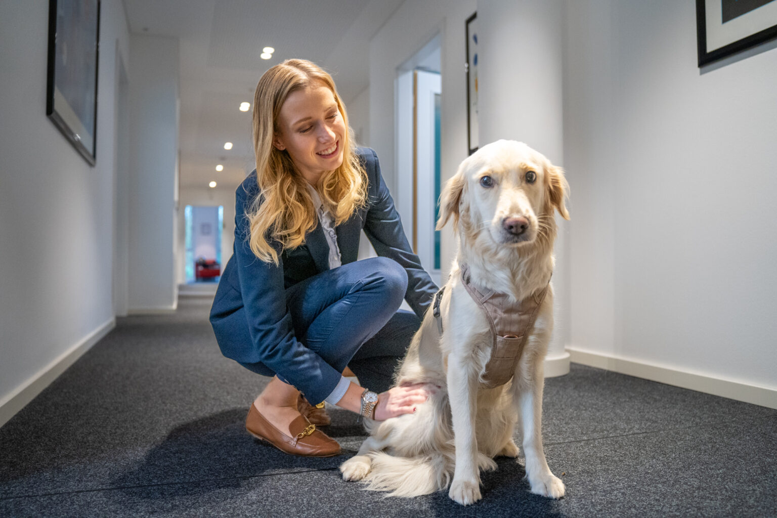 Frau kniet neben Hund im Flur der Kanzlei