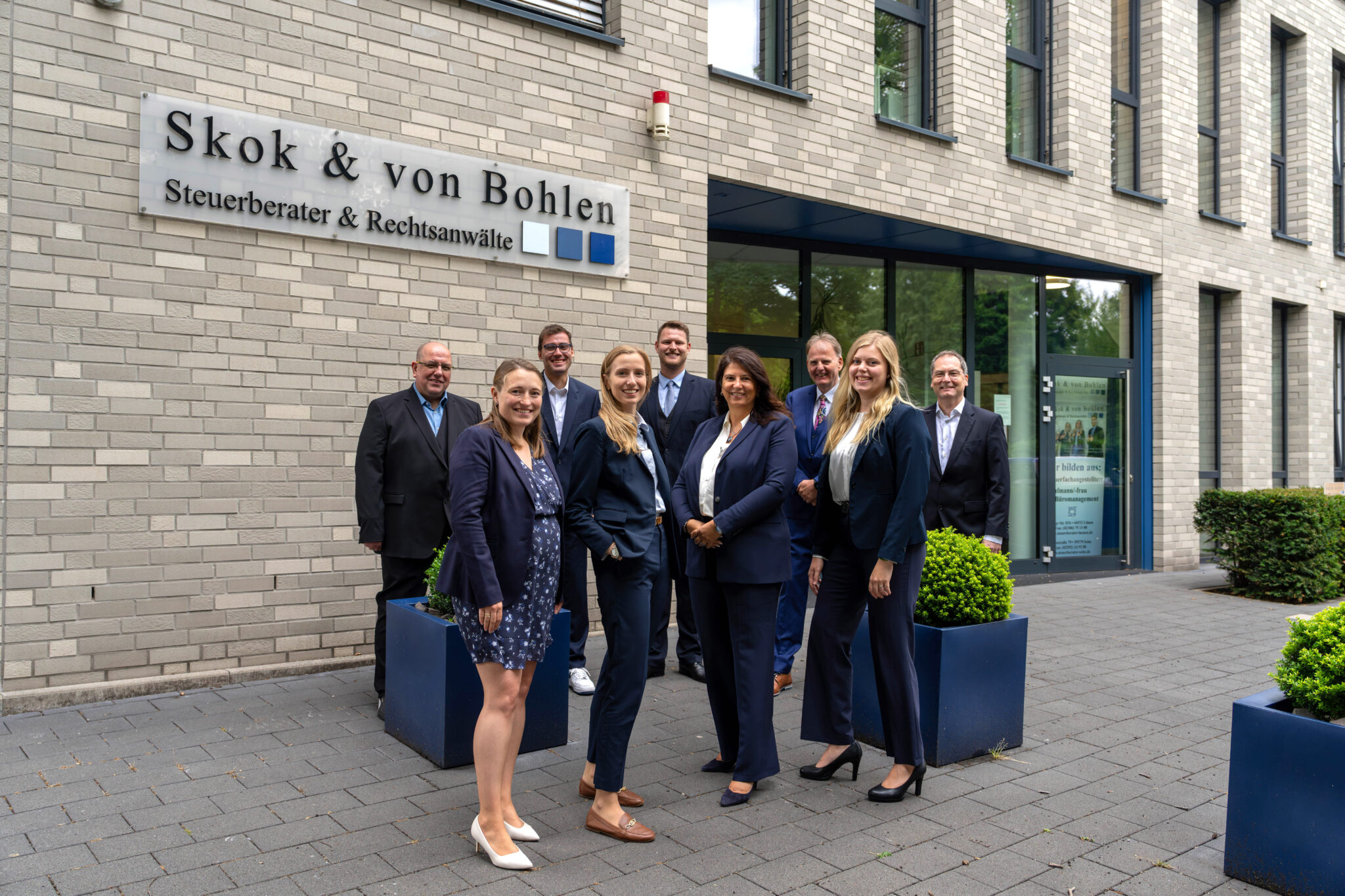 Gruppe von Personen steht vor dem Gebäude mit dem Kanzleischriftzug Skok & von Bohlen